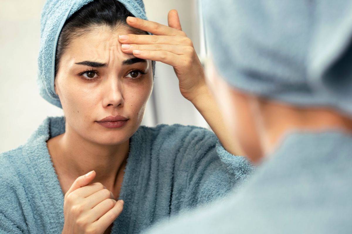 woman looks at mirror, unhappy